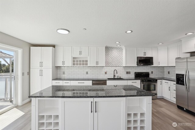 kitchen featuring decorative backsplash, white cabinets, sink, appliances with stainless steel finishes, and light hardwood / wood-style flooring