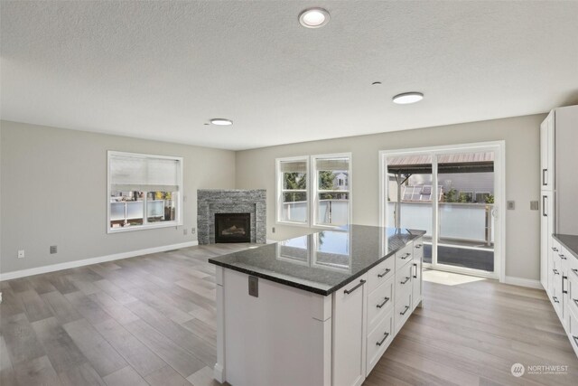 kitchen with white cabinetry, a fireplace, hardwood / wood-style floors, a center island, and a textured ceiling