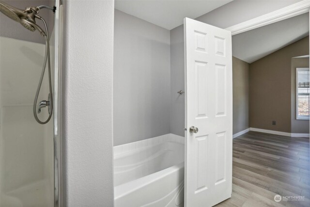 bathroom featuring vaulted ceiling, plus walk in shower, and hardwood / wood-style floors