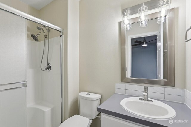 bathroom featuring vanity, toilet, decorative backsplash, and an enclosed shower