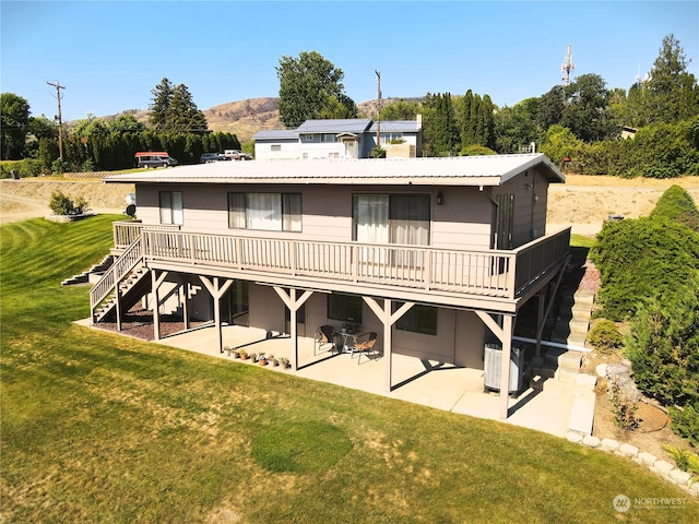 back of property with a wooden deck, a yard, central AC, and a patio