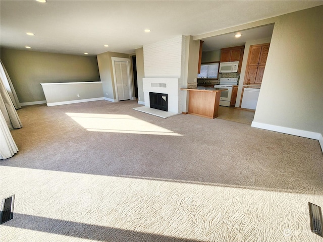 unfurnished living room with light colored carpet and a large fireplace