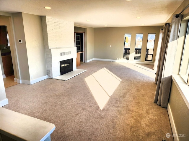 unfurnished living room featuring light carpet and a brick fireplace