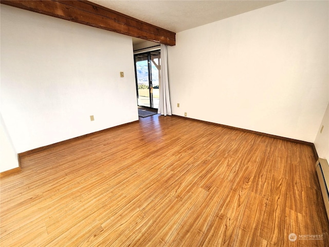 spare room with light wood-type flooring, beam ceiling, and baseboard heating