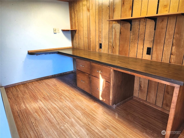 unfurnished office with built in desk and light hardwood / wood-style floors