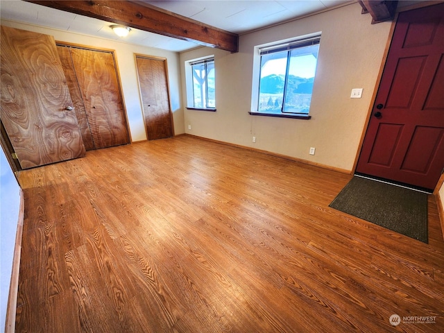 entryway with light hardwood / wood-style floors and beamed ceiling