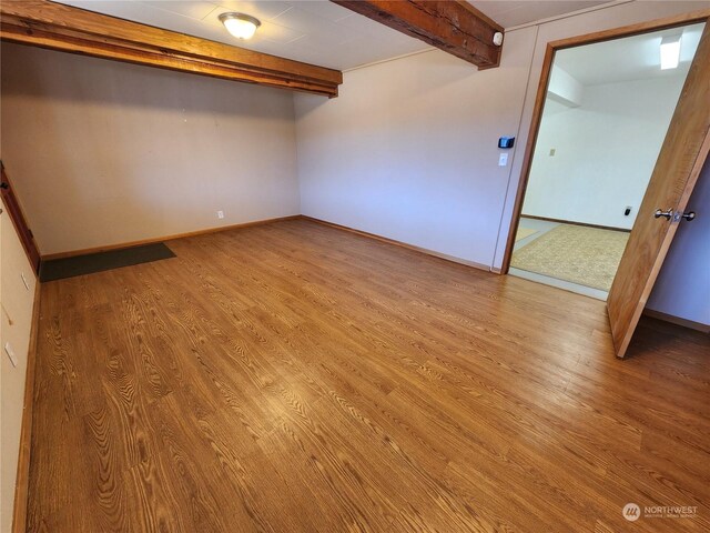 unfurnished bedroom with beamed ceiling and light hardwood / wood-style flooring