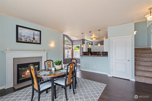 dining room featuring a tile fireplace, dark hardwood / wood-style floors, vaulted ceiling, and sink