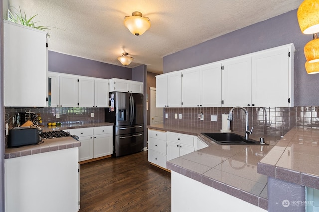 kitchen featuring backsplash, a textured ceiling, sink, white cabinets, and stainless steel fridge with ice dispenser