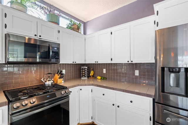 kitchen with tasteful backsplash, white cabinetry, stainless steel appliances, and a textured ceiling