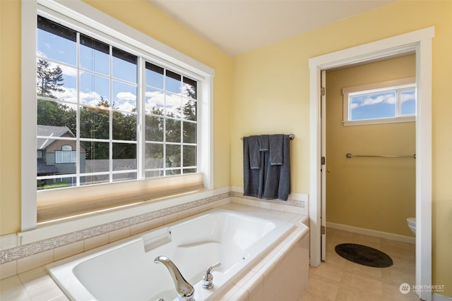 bathroom featuring tiled bath, tile patterned flooring, and toilet