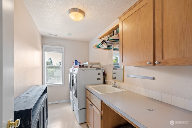 laundry room with washer and clothes dryer, cabinets, sink, and a textured ceiling