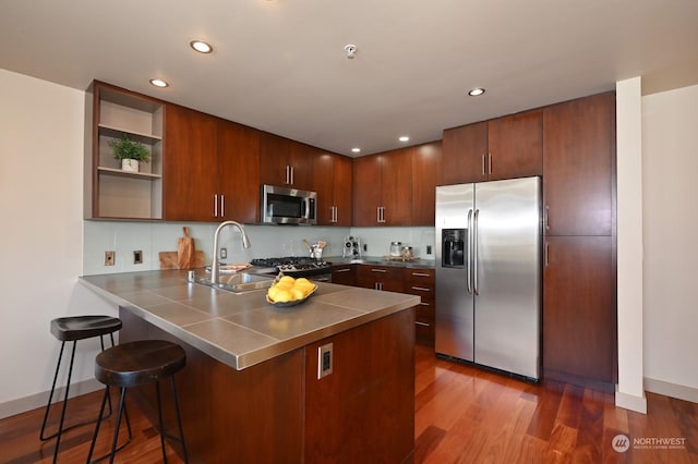 kitchen featuring stainless steel counters, sink, dark hardwood / wood-style flooring, kitchen peninsula, and appliances with stainless steel finishes