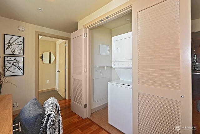 laundry room with wood-type flooring and stacked washing maching and dryer