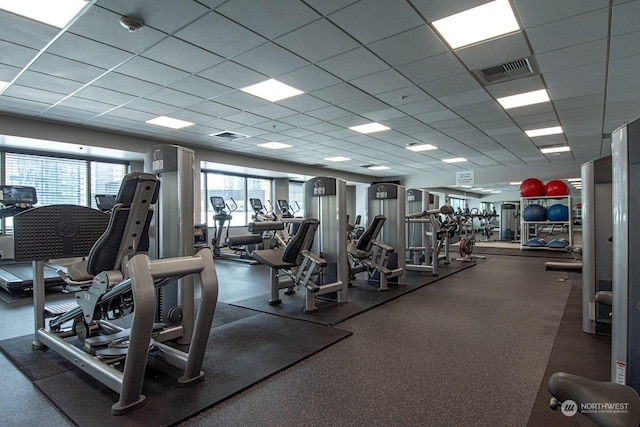 exercise room featuring a paneled ceiling and a healthy amount of sunlight