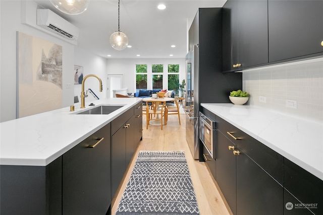 kitchen featuring decorative light fixtures, a wall mounted AC, light hardwood / wood-style floors, and sink