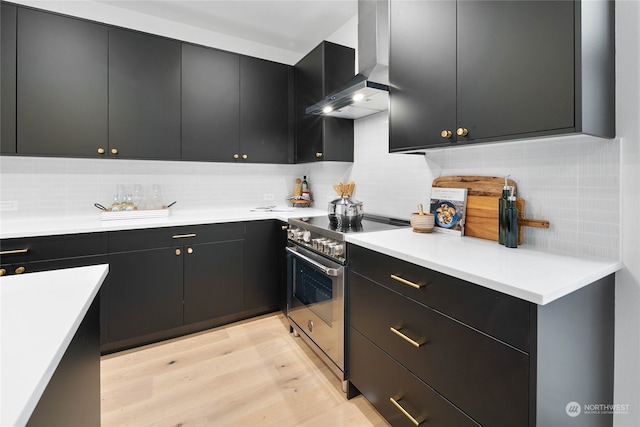 kitchen with decorative backsplash, light wood-type flooring, high end stainless steel range, and wall chimney range hood