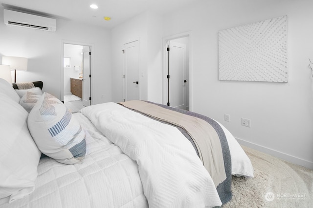 carpeted bedroom with a wall mounted air conditioner and connected bathroom