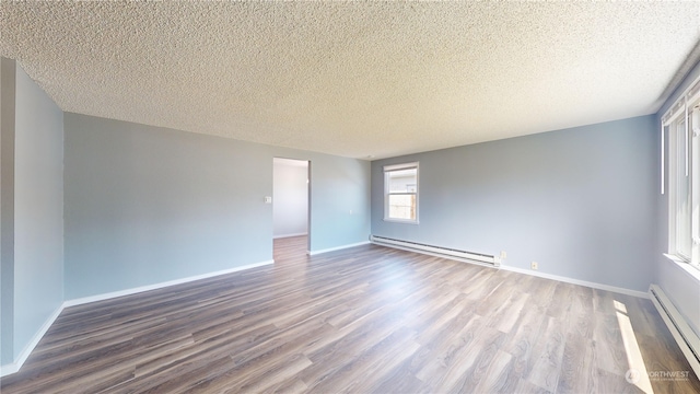 spare room featuring wood-type flooring, a textured ceiling, and a baseboard heating unit