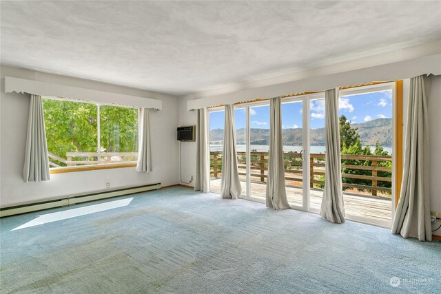 spare room featuring a baseboard heating unit, carpet, a water view, and a wall mounted air conditioner