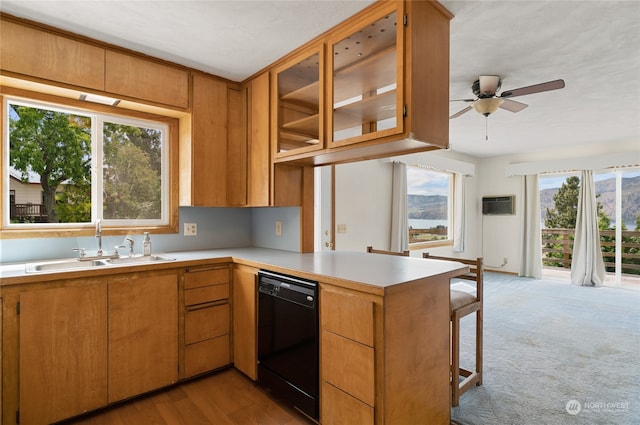 kitchen featuring ceiling fan, kitchen peninsula, black dishwasher, light colored carpet, and sink