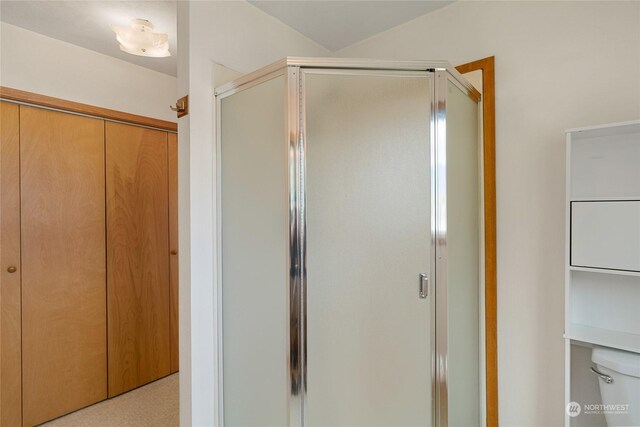 bathroom with a shower with shower door and toilet