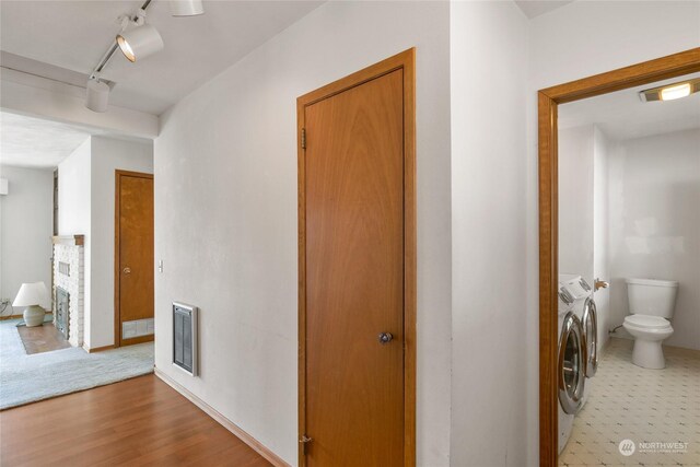 hall with hardwood / wood-style flooring, washing machine and dryer, and rail lighting