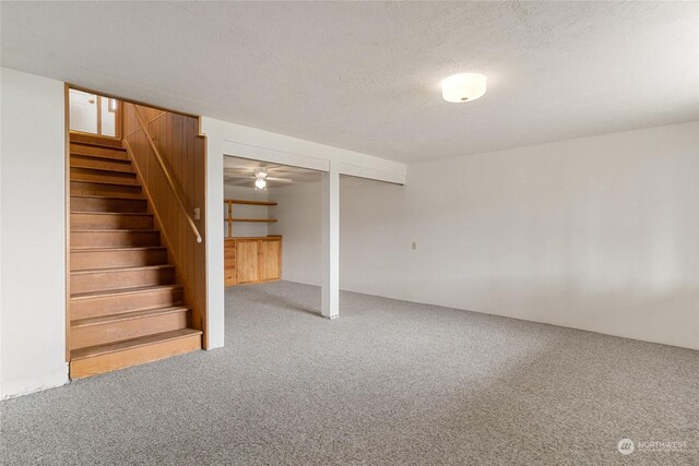 basement with a textured ceiling, carpet flooring, and ceiling fan