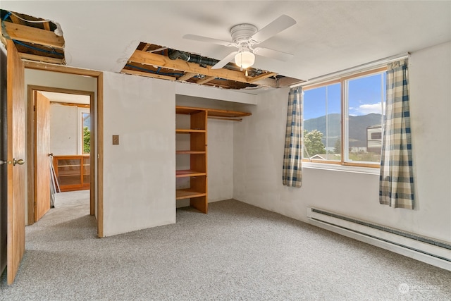 unfurnished bedroom featuring a baseboard radiator, a closet, carpet flooring, and ceiling fan