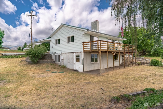 rear view of property featuring a yard and a wooden deck