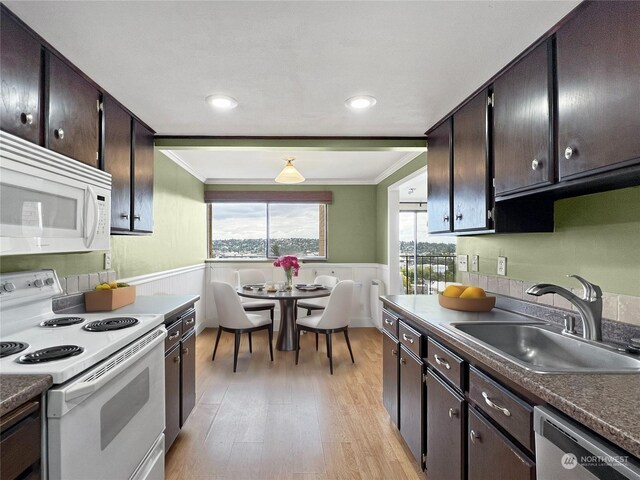 kitchen with white appliances, light wood-type flooring, dark brown cabinetry, ornamental molding, and sink