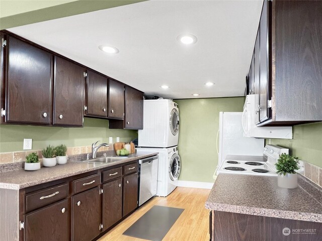 kitchen featuring stove, stainless steel dishwasher, light hardwood / wood-style flooring, stacked washer / drying machine, and dark brown cabinetry