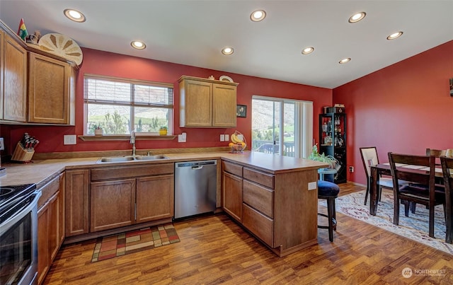 kitchen with dishwasher, sink, light hardwood / wood-style flooring, kitchen peninsula, and electric stove