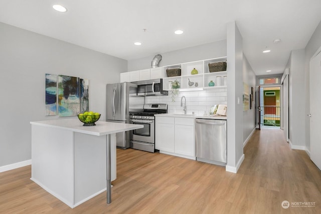 kitchen featuring sink, tasteful backsplash, light hardwood / wood-style flooring, white cabinets, and appliances with stainless steel finishes