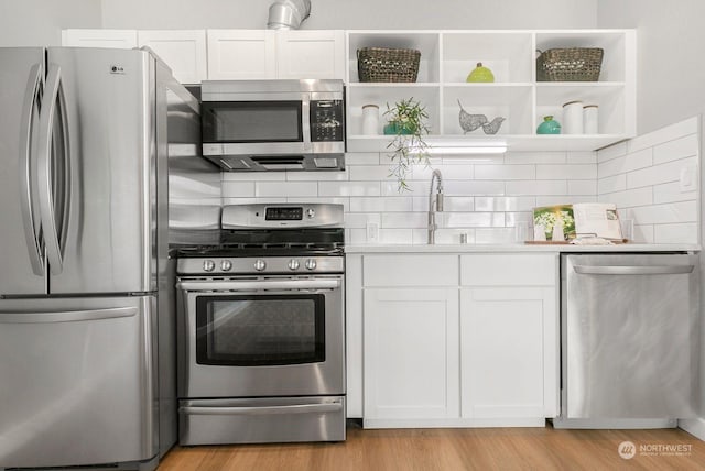 kitchen featuring appliances with stainless steel finishes, light wood-type flooring, white cabinetry, and sink