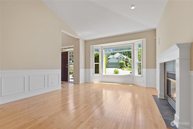 unfurnished living room featuring a tile fireplace, hardwood / wood-style floors, and lofted ceiling