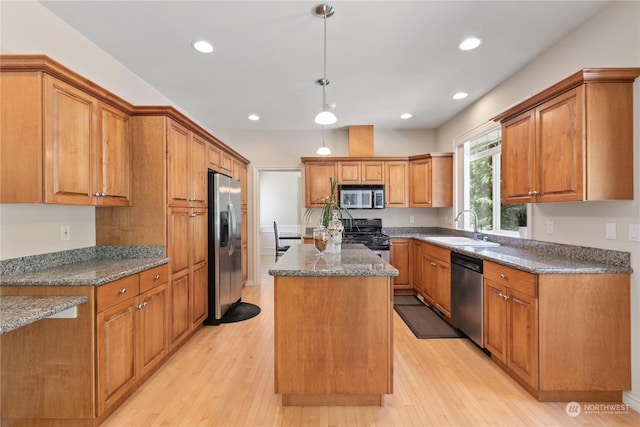 kitchen with appliances with stainless steel finishes, dark stone counters, sink, a center island, and hanging light fixtures