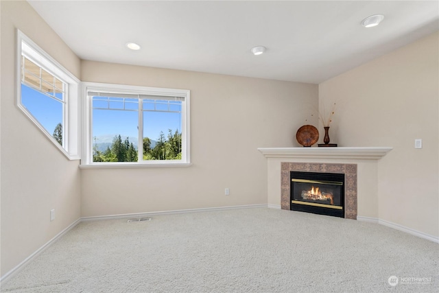 unfurnished living room featuring a tile fireplace and carpet