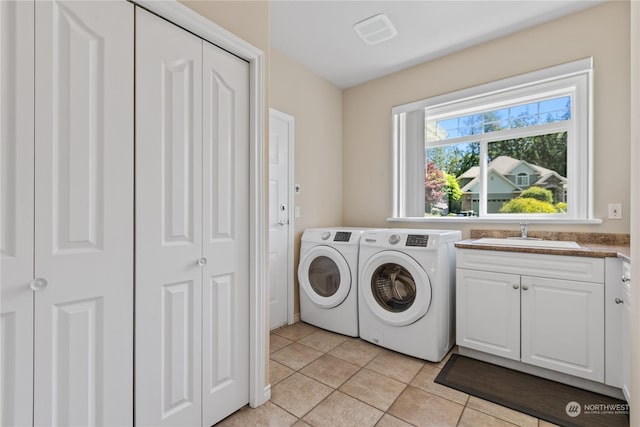 laundry area with cabinets, light tile patterned floors, sink, and washing machine and clothes dryer