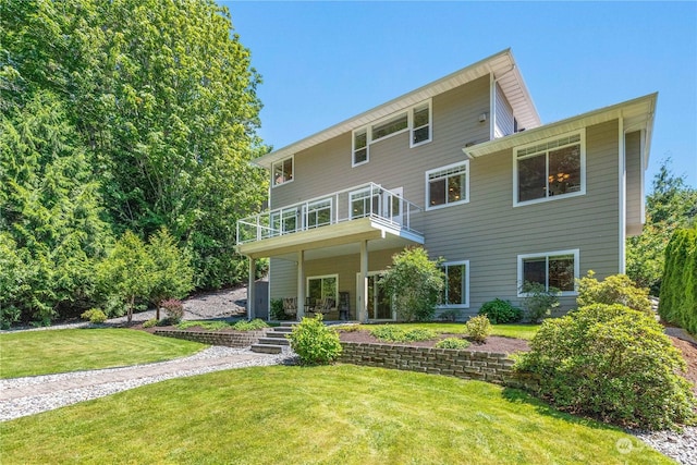 back of property featuring a balcony and a yard