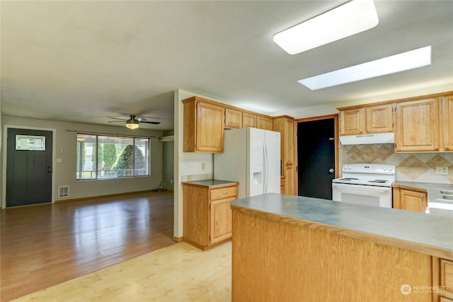 kitchen with white appliances, a skylight, decorative backsplash, ceiling fan, and light wood-type flooring