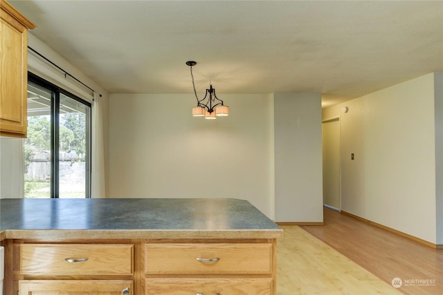 kitchen with light brown cabinetry, light hardwood / wood-style flooring, hanging light fixtures, and a notable chandelier