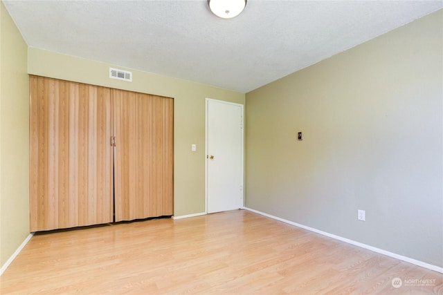 unfurnished bedroom featuring light hardwood / wood-style flooring and a closet