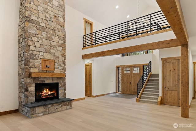 unfurnished living room featuring a fireplace, light hardwood / wood-style floors, and a high ceiling