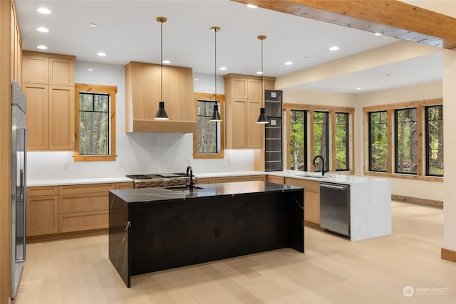 kitchen featuring sink, stainless steel appliances, decorative light fixtures, a kitchen island with sink, and light brown cabinetry