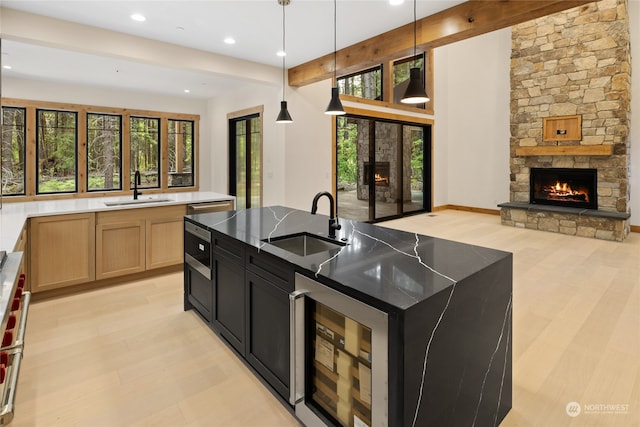 kitchen with a center island with sink, a fireplace, sink, and hanging light fixtures