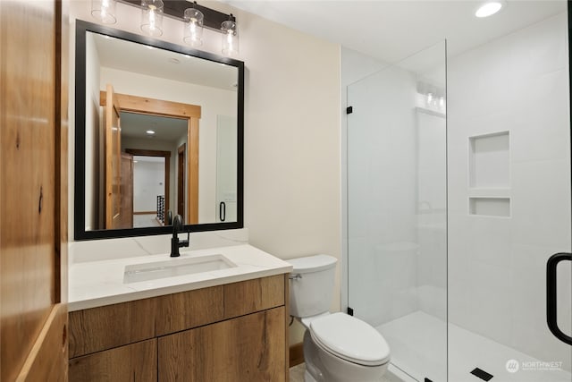 bathroom with vanity, toilet, and a shower with door