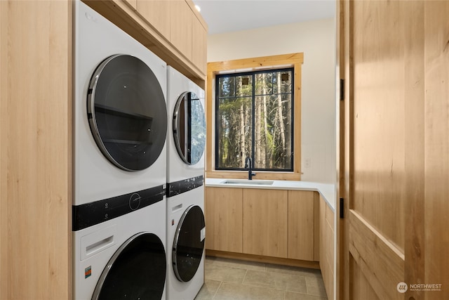 laundry area with light tile patterned flooring, sink, and stacked washer and dryer