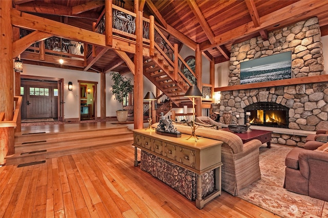 living room with high vaulted ceiling, wooden ceiling, hardwood / wood-style flooring, and a fireplace