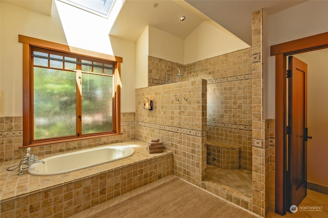 bathroom featuring independent shower and bath, lofted ceiling with skylight, and a wealth of natural light